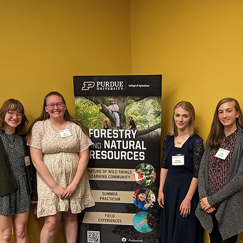 Four students standing by FNR Nature of Wild Things banner, FNR Student Annual Awards and Scholarship Ceremony. 