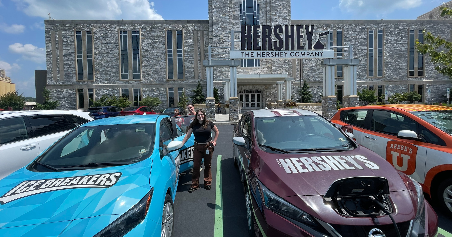 Barbara Montemayor Martinez stands next to Hershey-branded car in front of The Hershey Chocolate Company