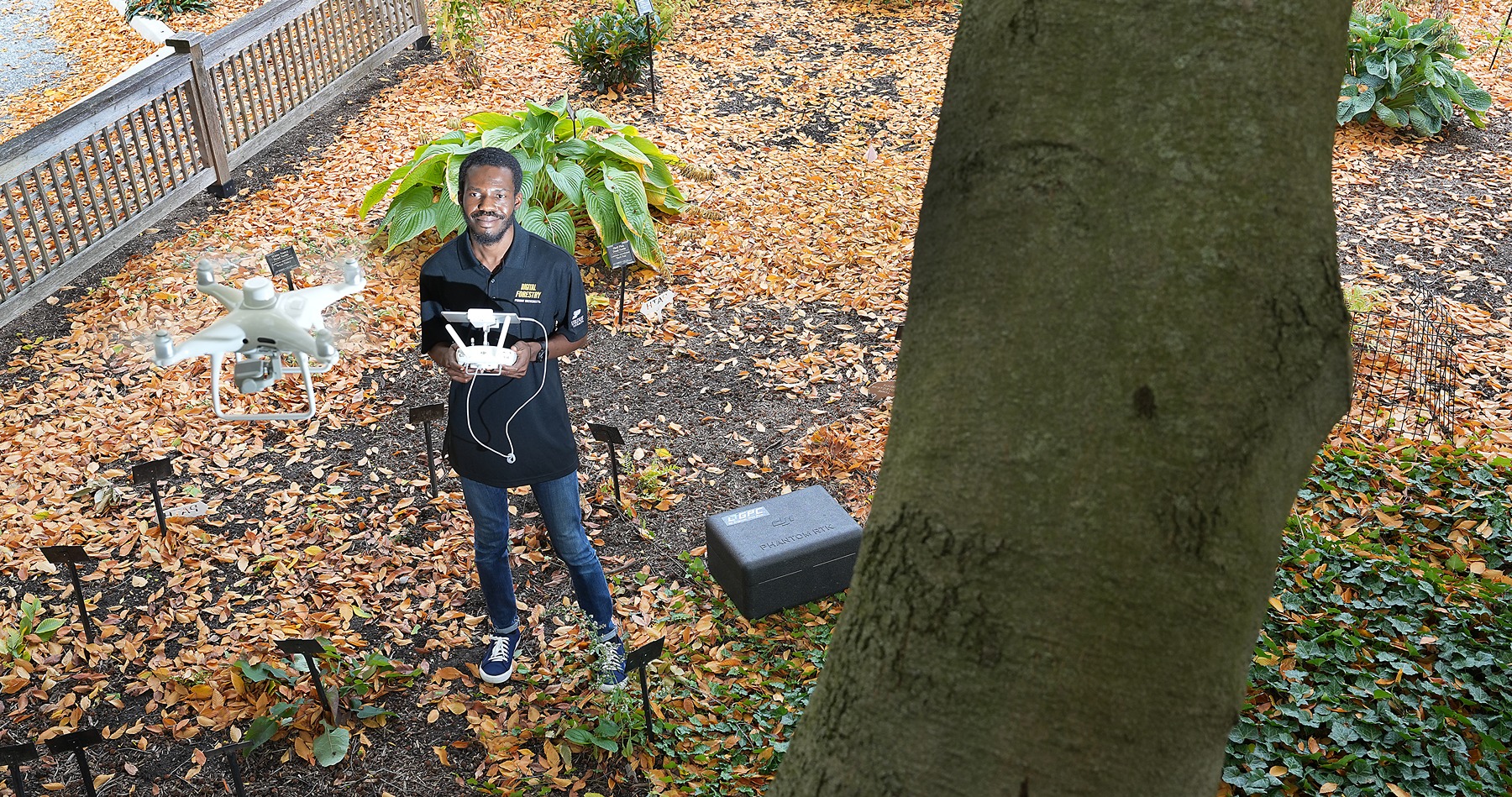 Ismail Olaniyi flies a UAV up above the trees.