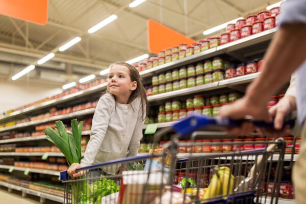 Young girl grocery shopping with father.
