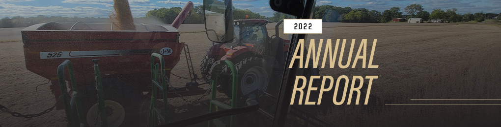 Grain cart and tractor next to combine in field during harvest. Cover to the 2022 Annual Report.