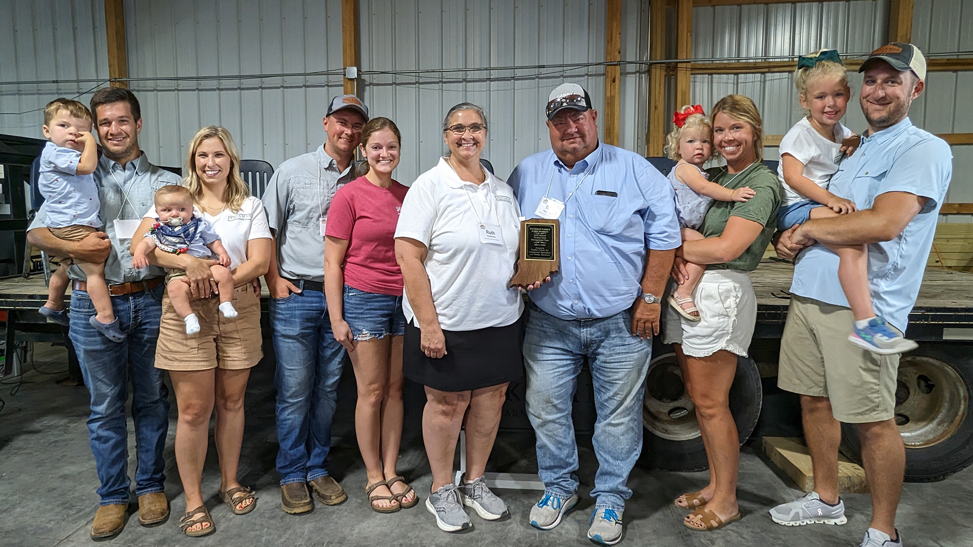 Hackman family with Purdue Farm Management Tour plaque, in front of stage on July 11, 2023.