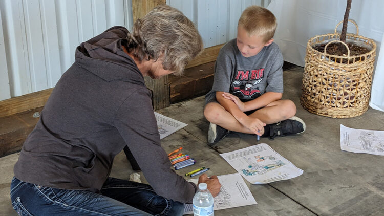 Woman and young boy coloring during the Purdue Farm Management Tour.