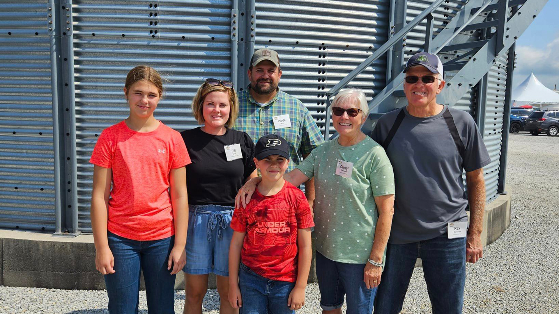 Family photo of Wade and Jill Miller with their children and Rex and Cheryl Clements in front of grain bins during the Purdue Farm Management Tour on July 17, 2024.