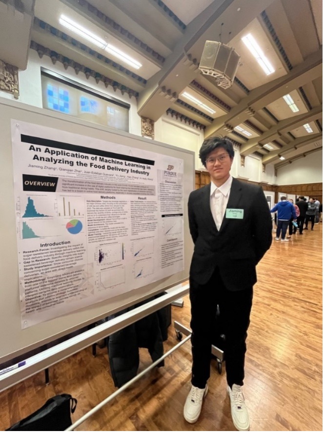 Zhang standing next to presentation poster on machine learning 
