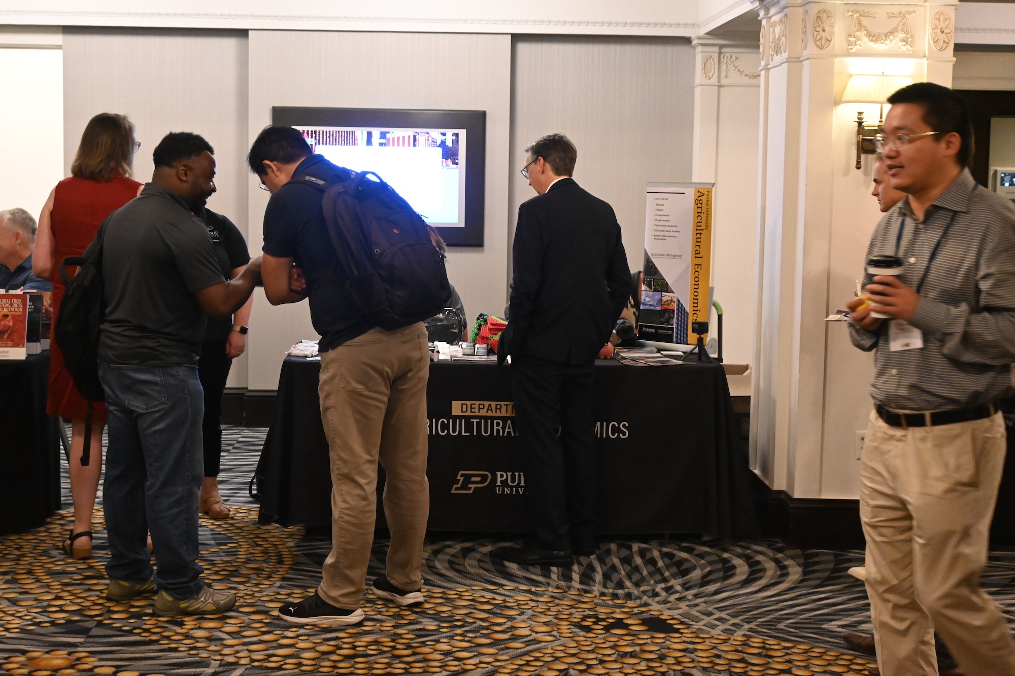 Group of AAEA attendees standing around the ag econ exhibit table