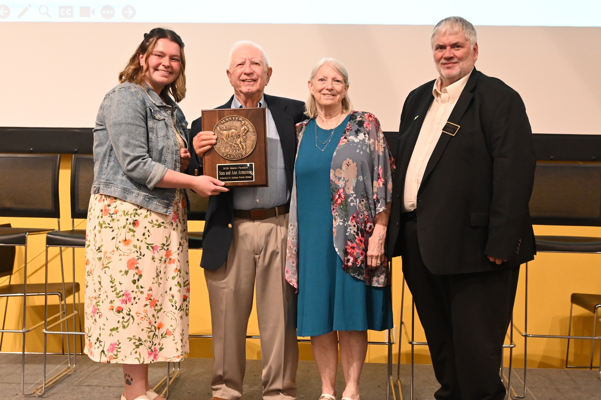 Allison Lynch and Dean Engel standing with Stan and Ann Armstrong holding their Master Farmer award