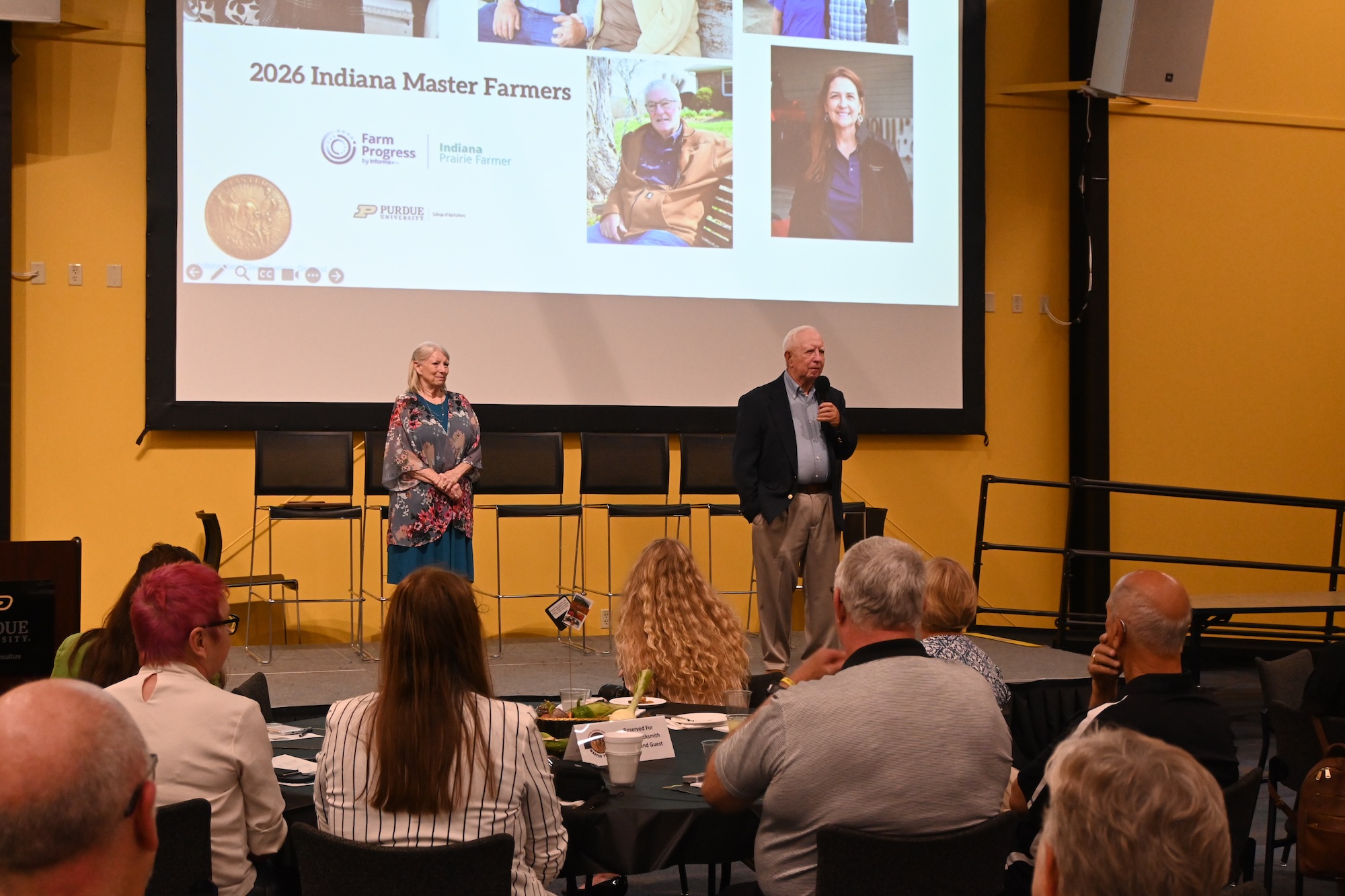  Stan Armstrong talking on stage beside his wife, Ann