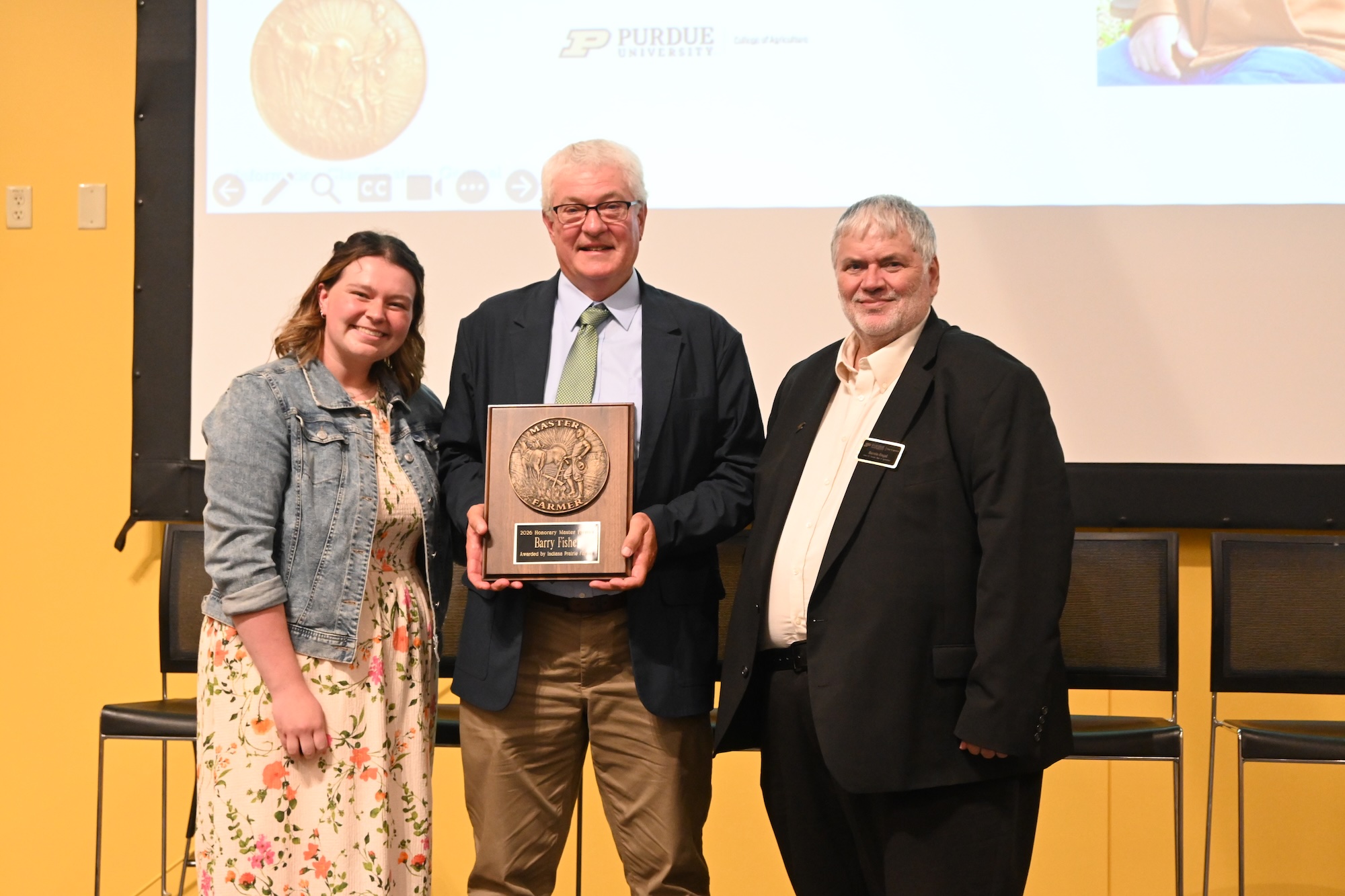 Allison Lynch and Dean Engel standing with Barry Fisher holding his Honorary Master Farmer award