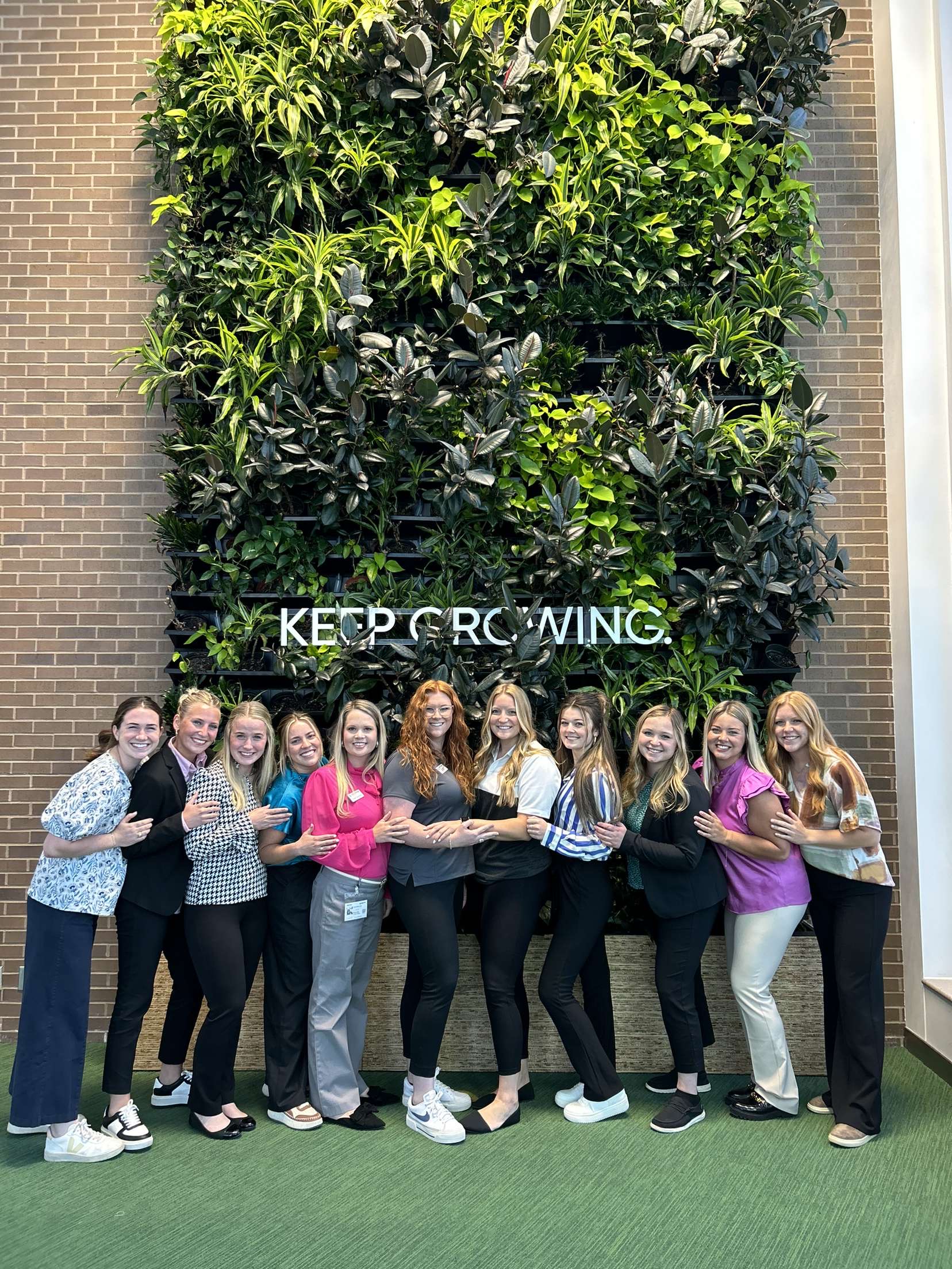 Shay with friends in front of Keep Growing sign