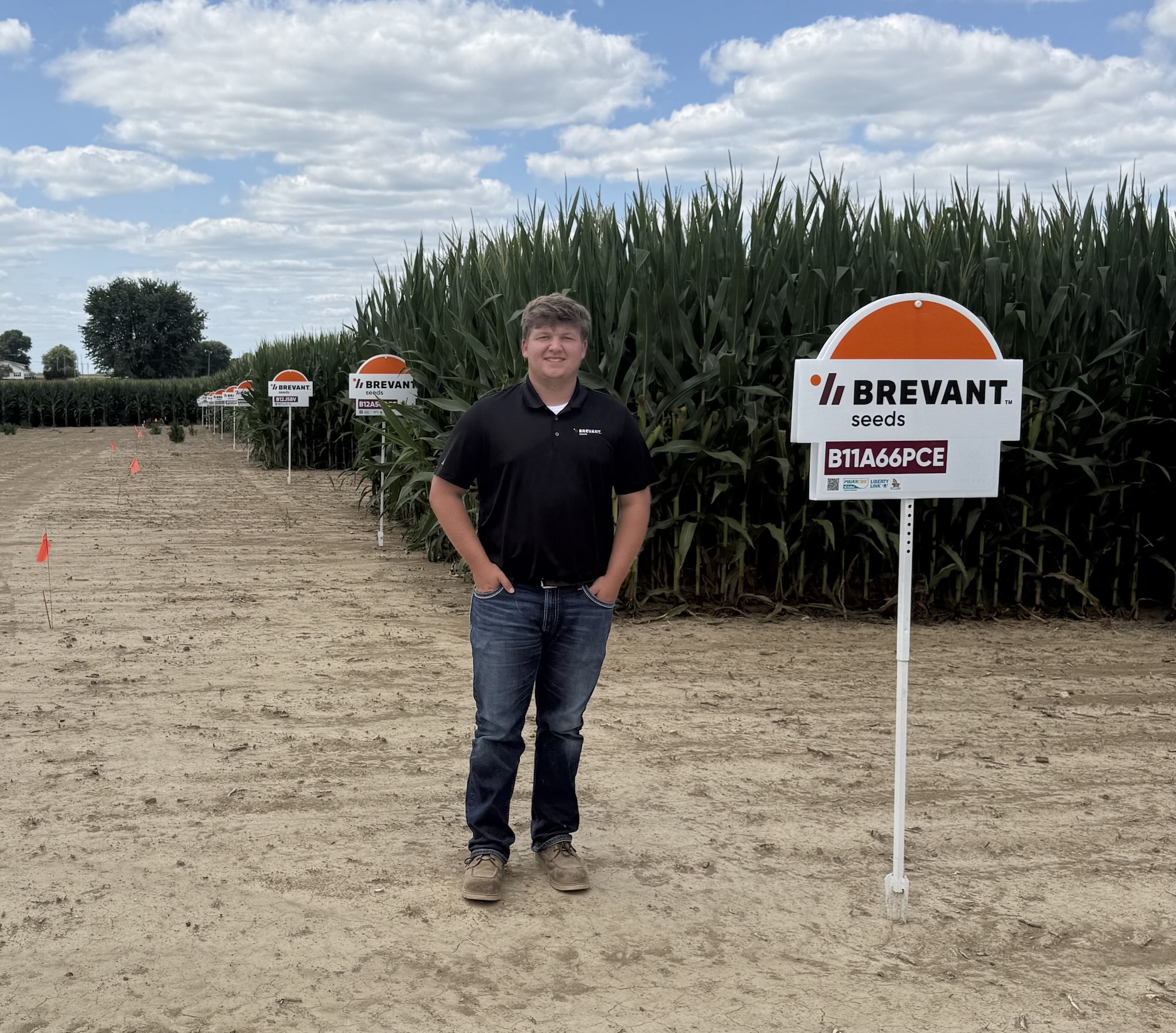Alberring in a corn field standing next to a Brevant seeds sign