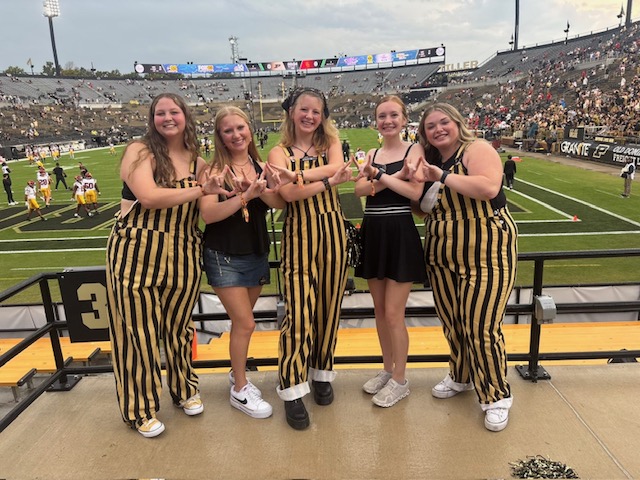 Anglemyer with friends wearing striped overalls in Ross-Ade Stadium 