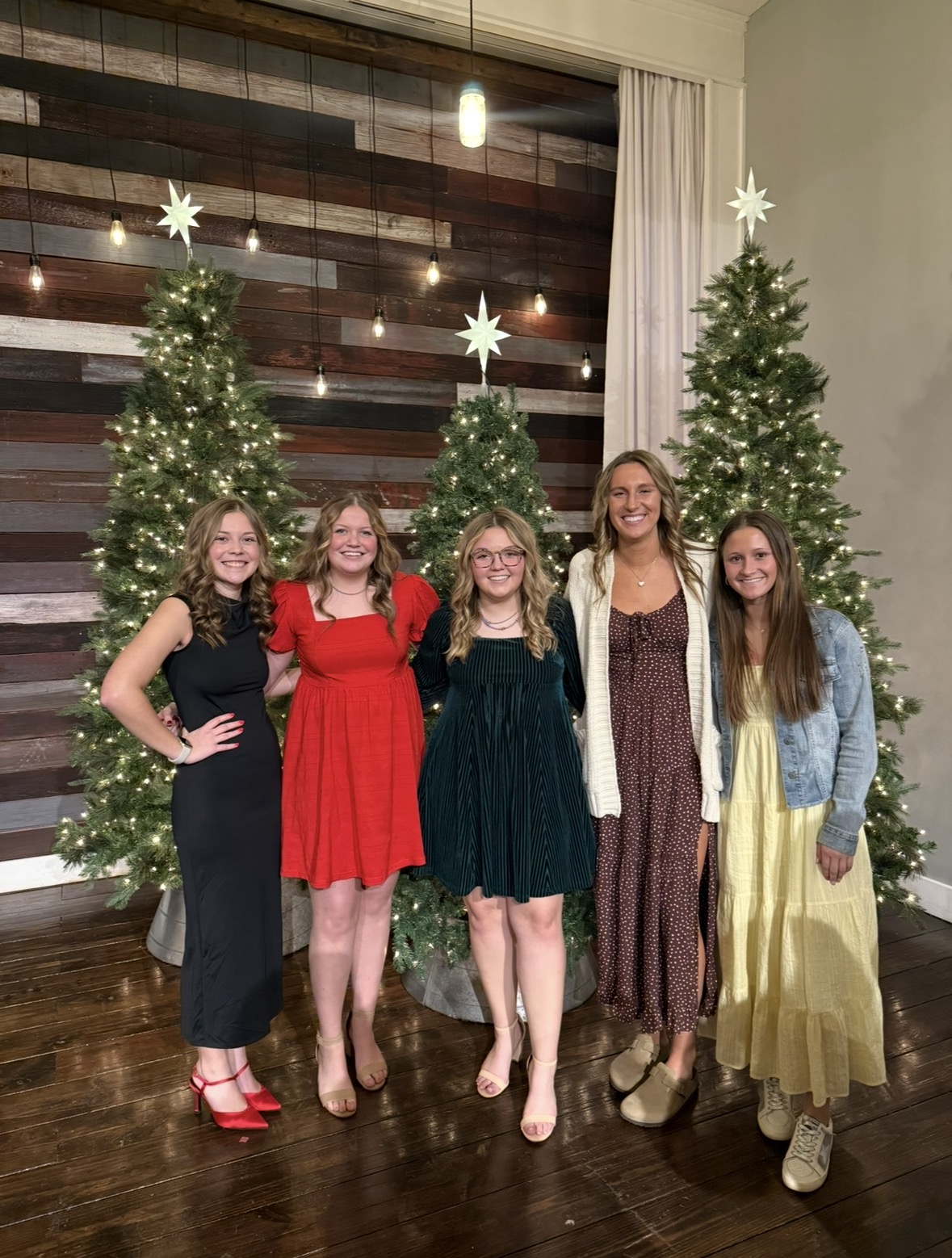 Cooper with friends in front of a Christmas tree backdrop