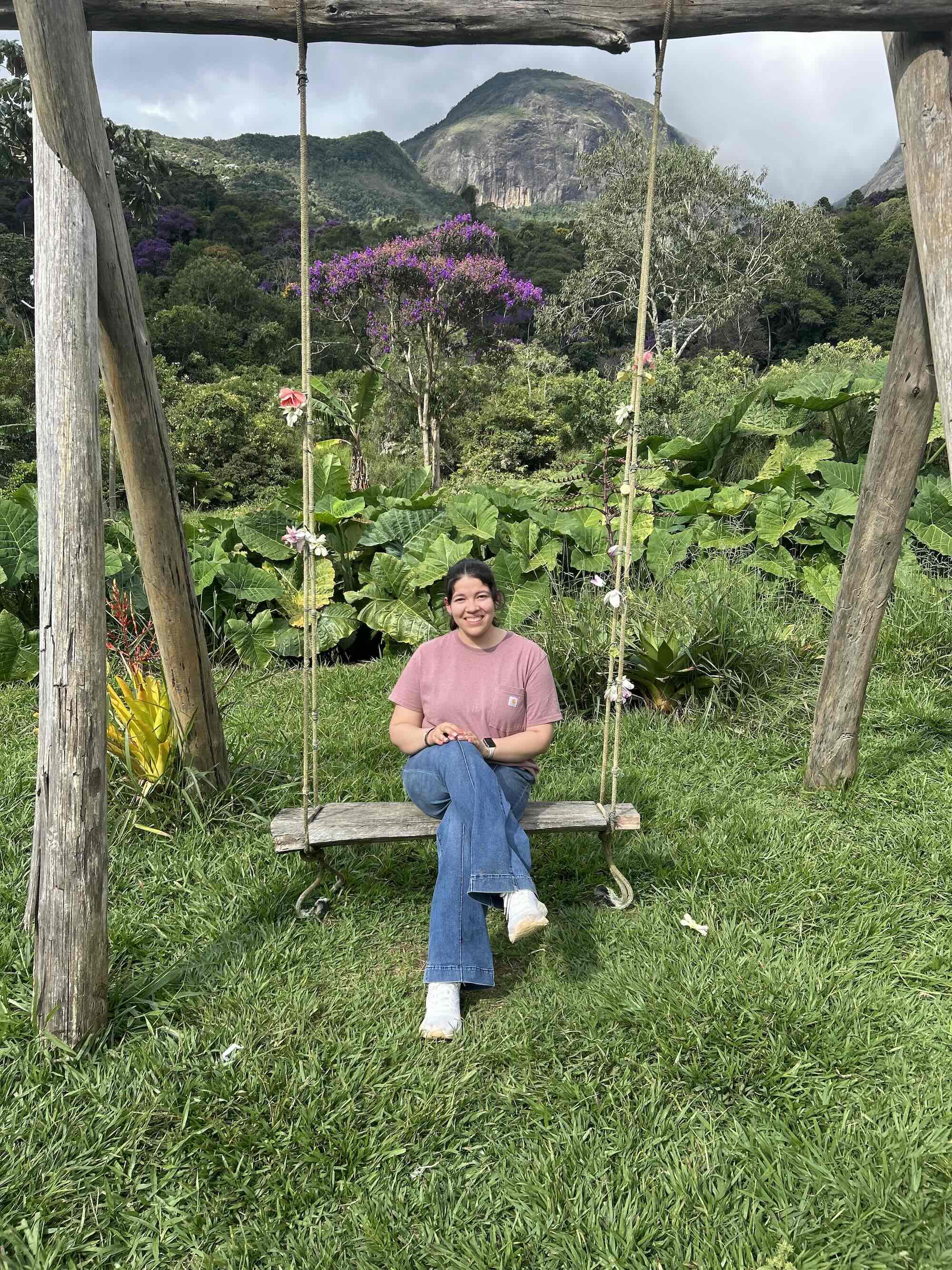 Berenize sitting on a large outdoor wooden swing