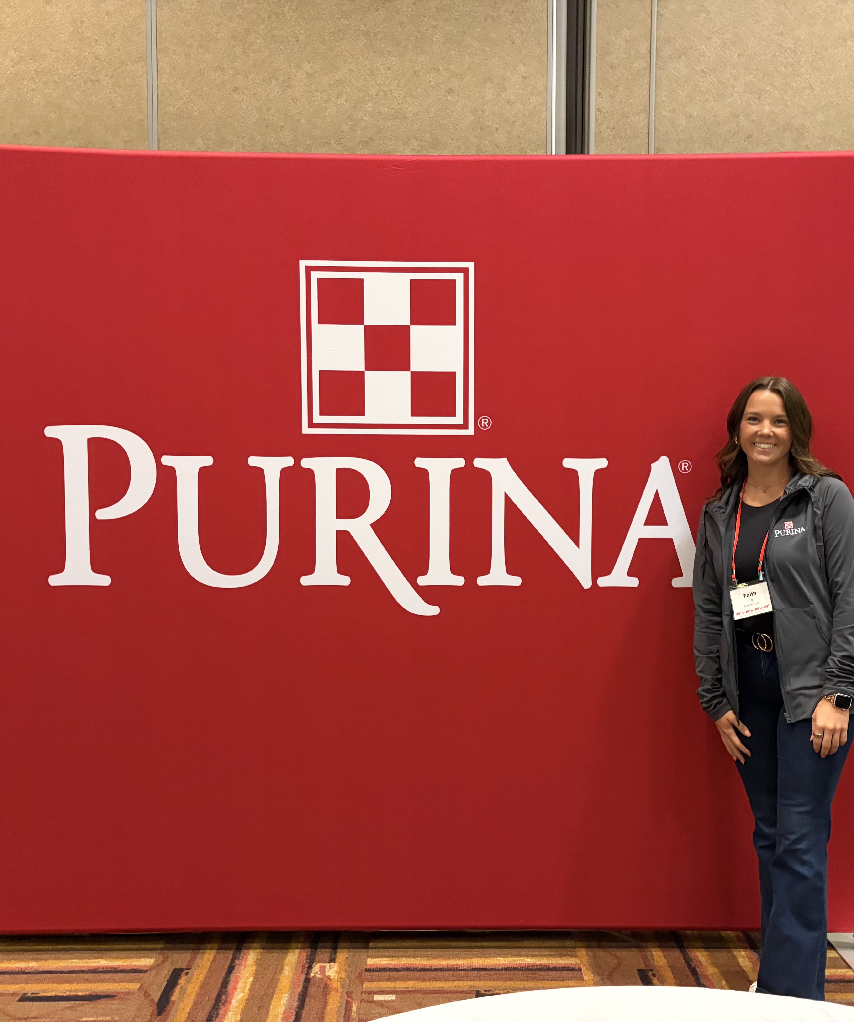 Frey standing in front of a red Purina sign for an internship