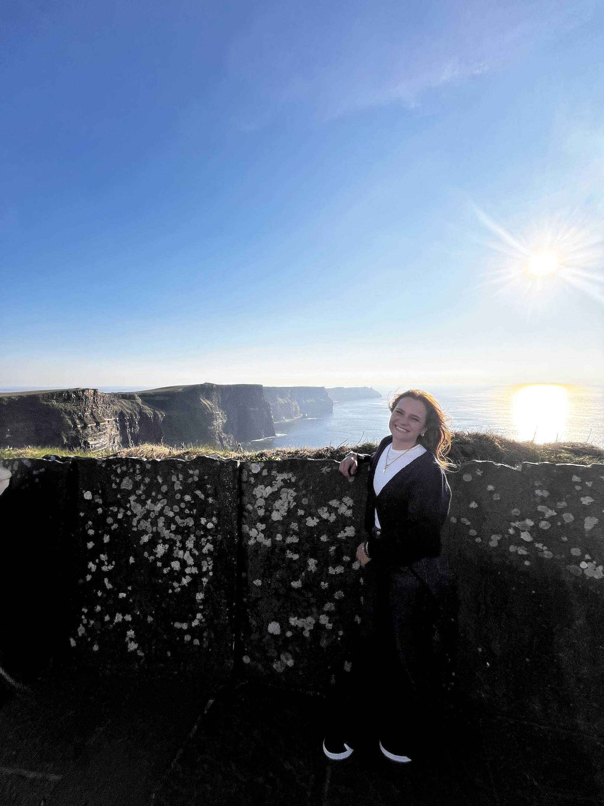 Kelsay standing atop a cliff overlooking the ocean in Ireland