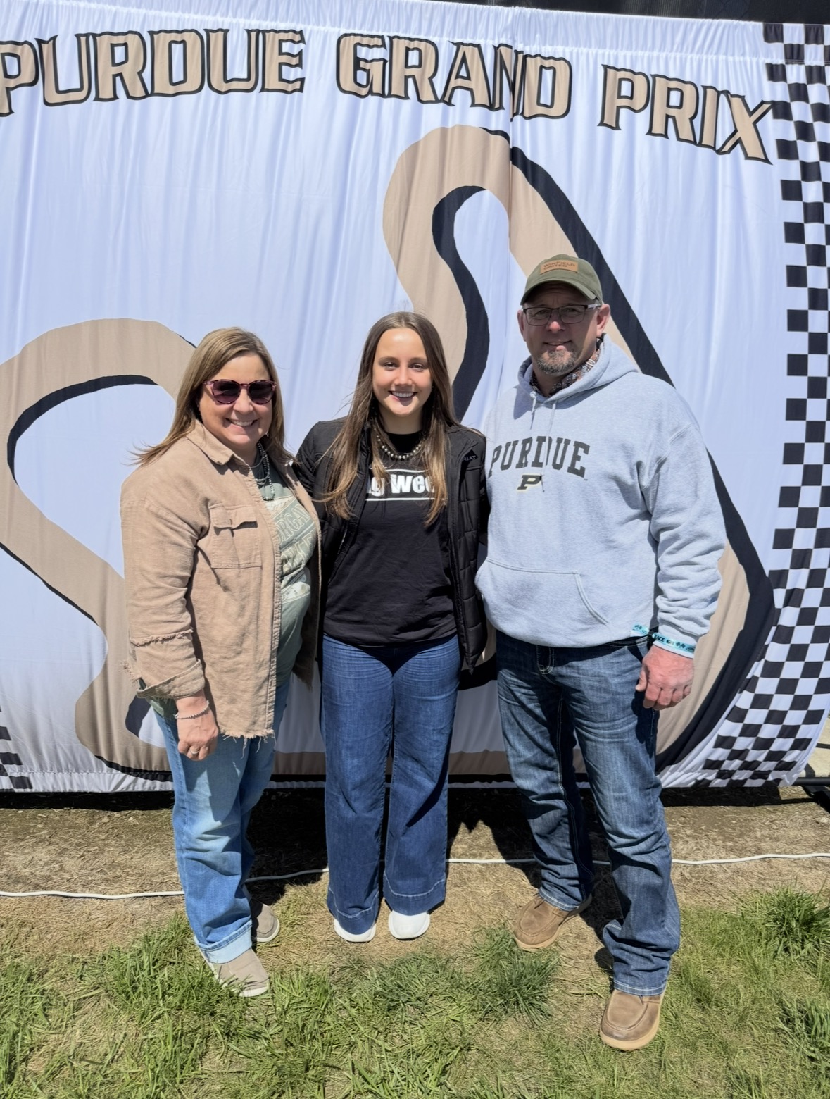 Markley standing with family in front of Purdue Grand Prix banner