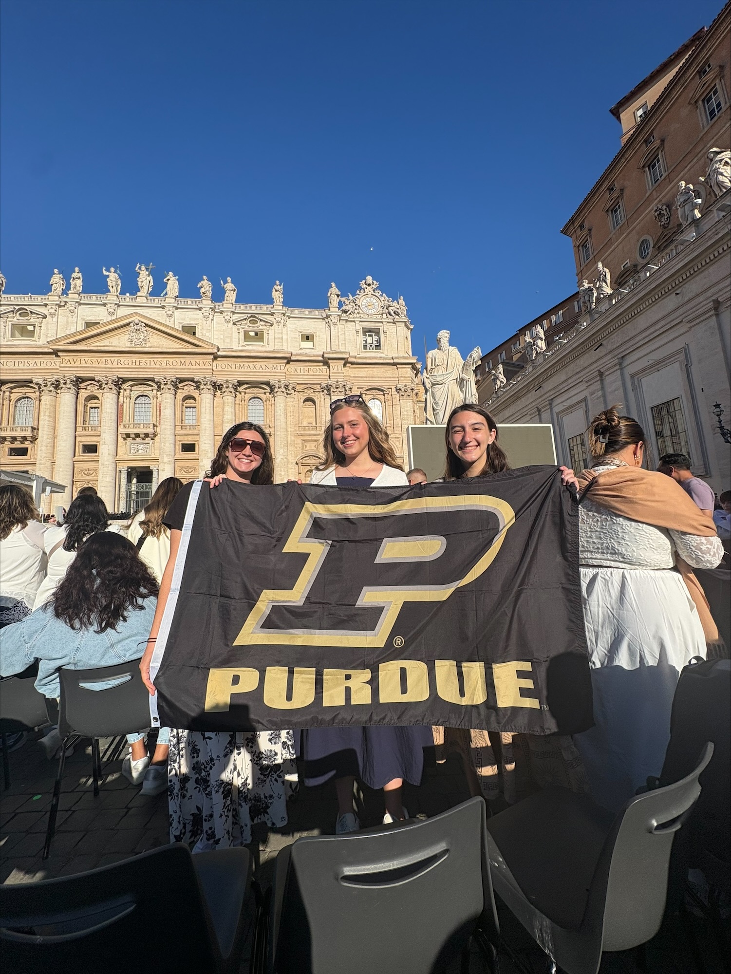 Recker holding Purdue flag with friends while on study abroad