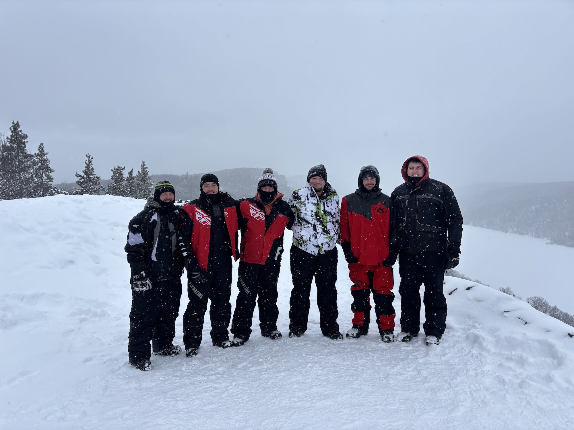 Rooze with friends in snow gear atop a snowy mountain