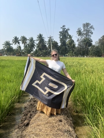 Bothwell standing with Purdue flag in tea field