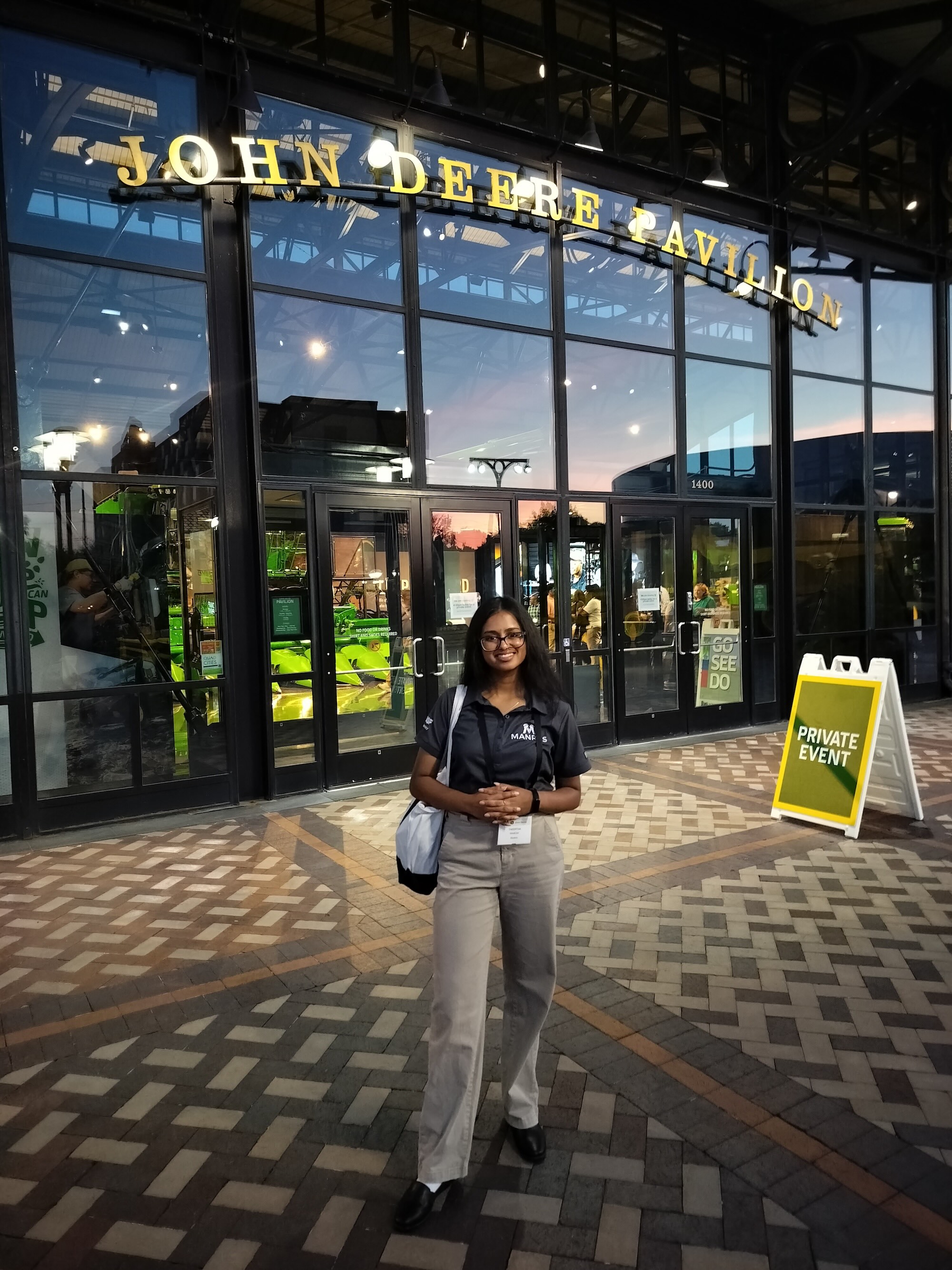 Theertha standing in front of the John Deere Pavilion