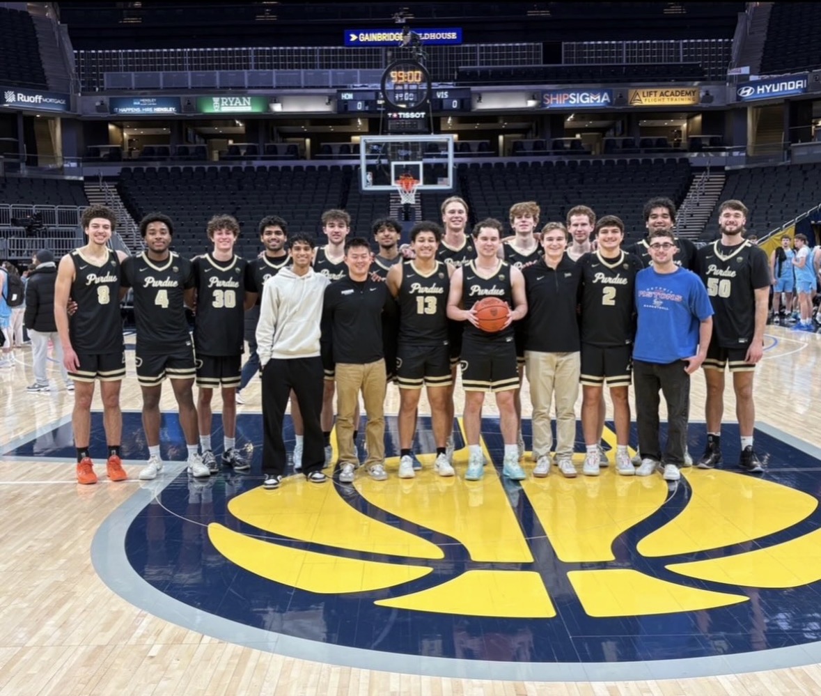 Purdue basketball club standing for a group photo on the Pacers basketball court