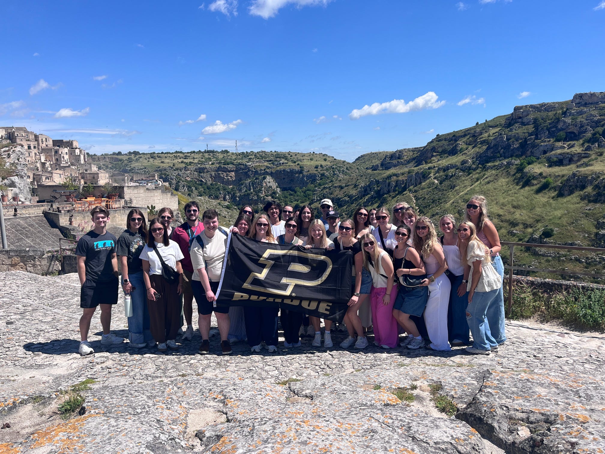 Study abroad group posing in front of Italian city and cliffs