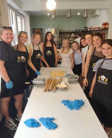 Study abroad group standing in a kitchen making pasta