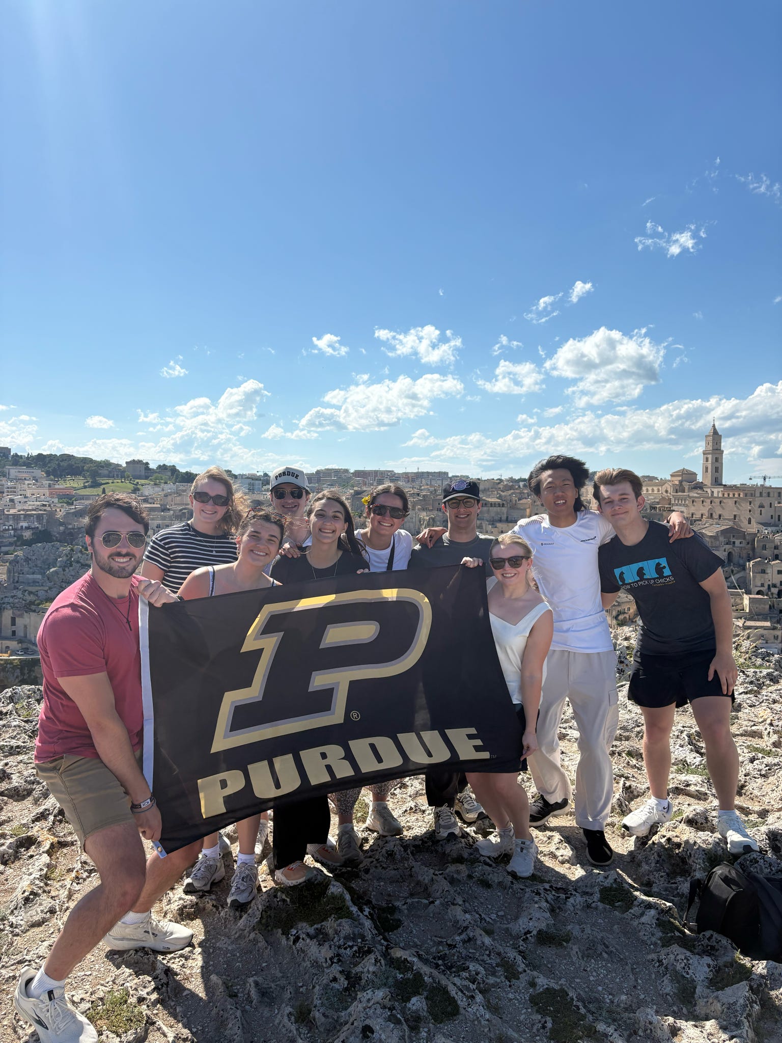 Study abroad group standing on rocks in front of Italian city