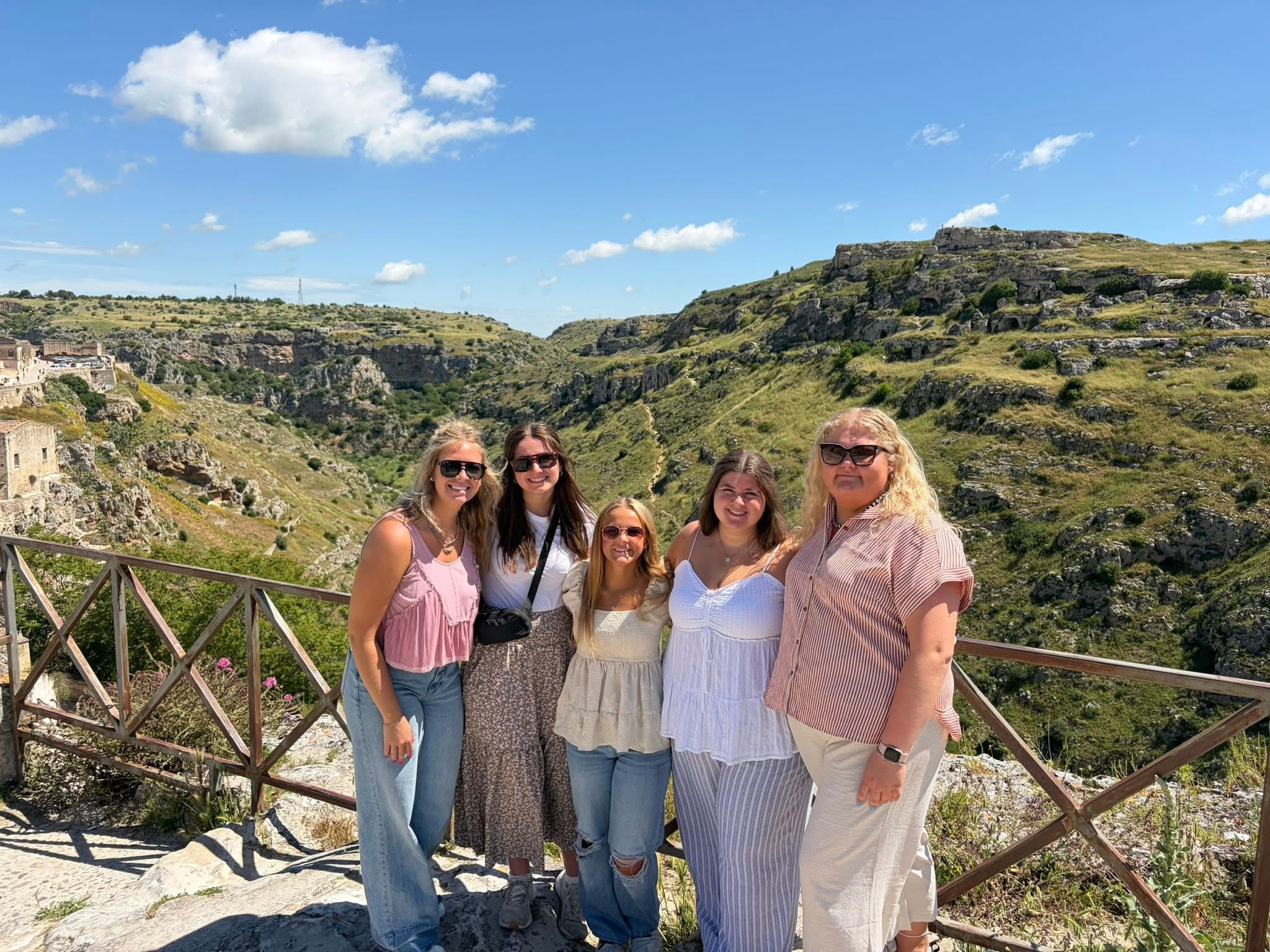 Small group standing on top of cliff overlooking Italian city