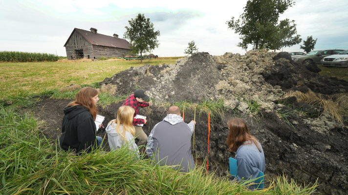 professor and students in a soil pit