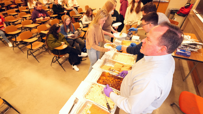 professor serving assortment of international foods to students