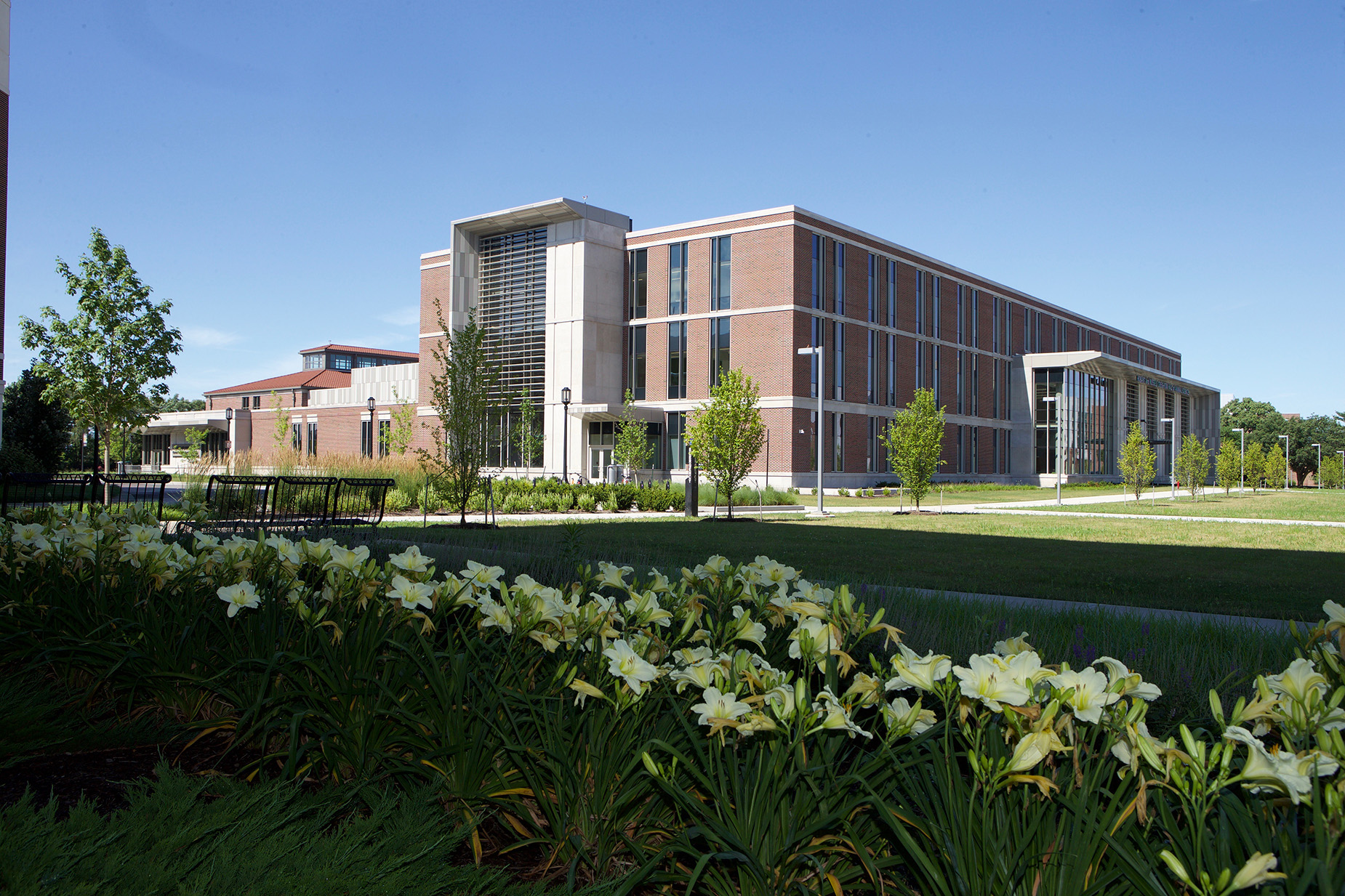 Creighton Hall of Animal Sciences on Purdue’s campus with landscaped lawn and flowers under a clear blue sky.