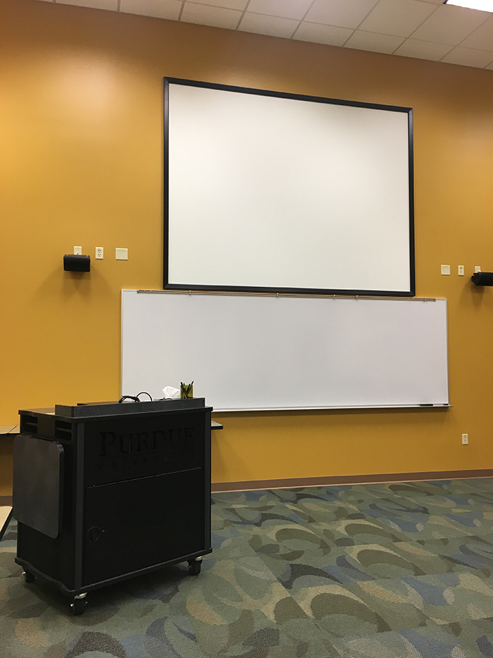 Room 141 white board with projector screen above used for presentations