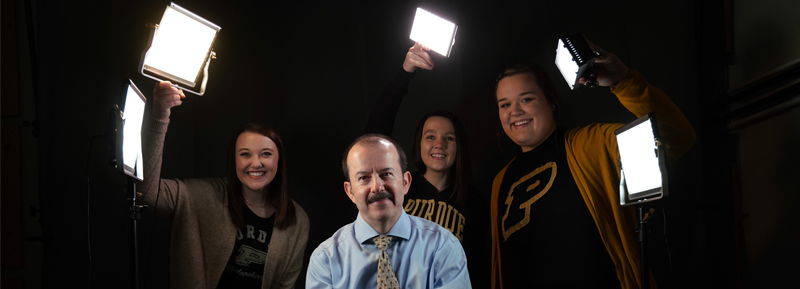 Agricultural Communication students hold studio lights to spotlight Dr. Mark Tucker