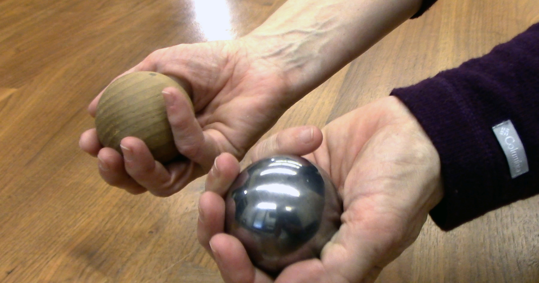 Hands holding balls made of wood and metal