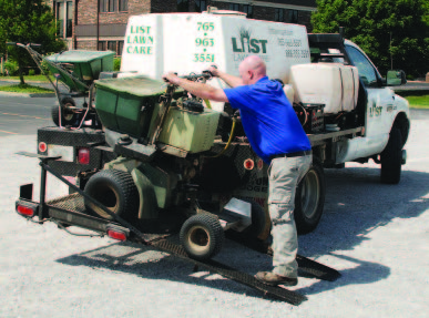 Person loading ride-on sprayers onto carrier