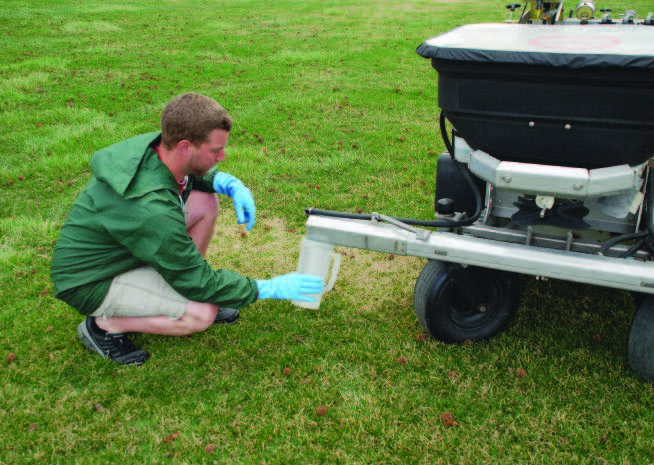 Person measuring the number of fluid ounces delivered from each nozzle for the length of time it took to travel the calibration course.