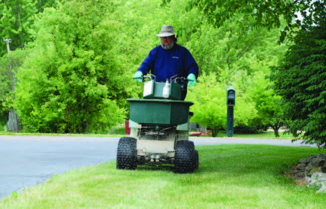 Man usig edge guard barrier to spray fertilizers