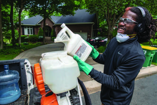 man pouring insecticide mix into back pack mist blower