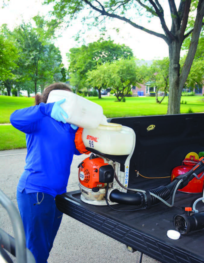 woman pouring insecticide mix into back pack mist blower