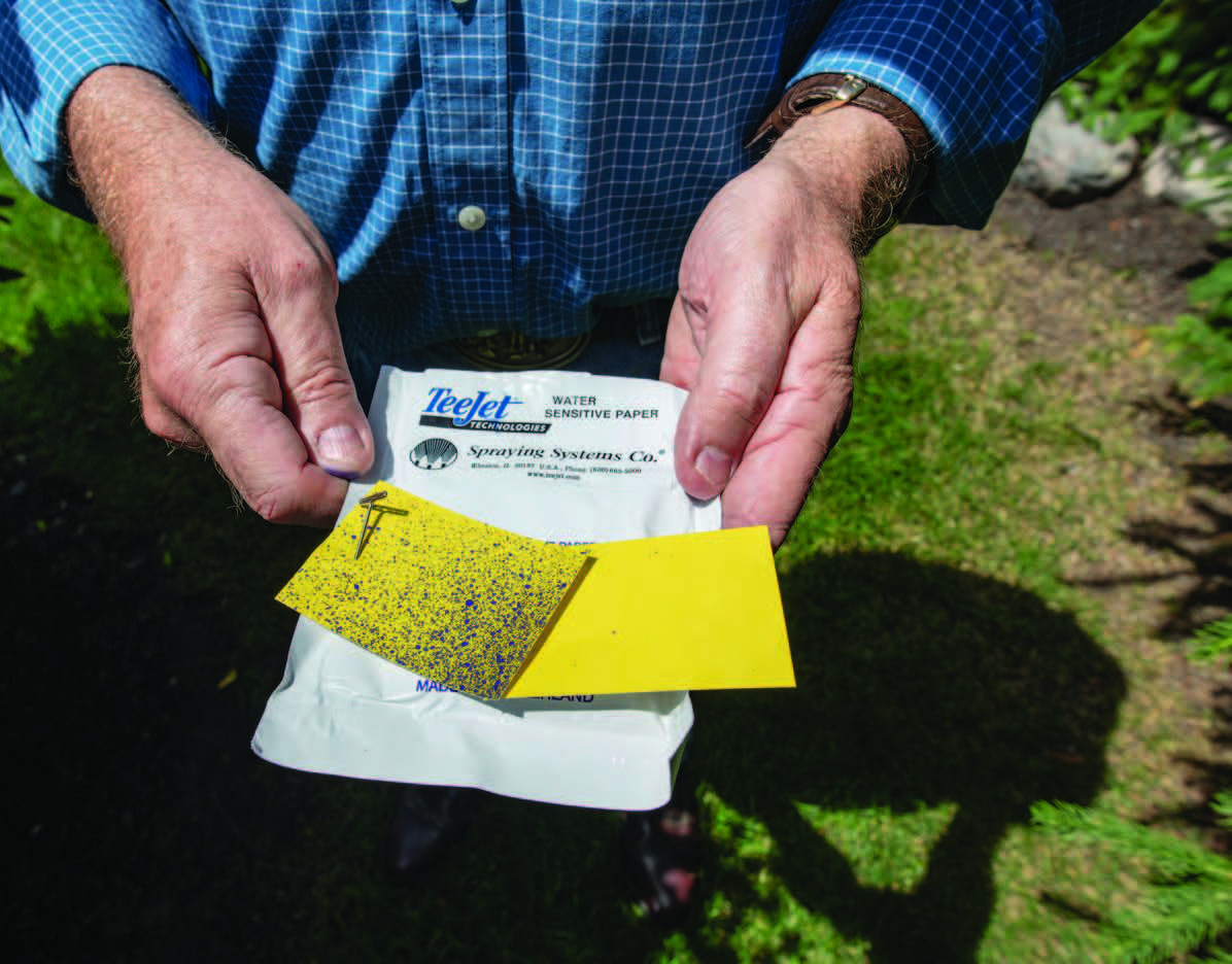 2 yellow cards comparing coverage from spraying near the plant’s base.