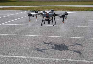 A drone sprays two feet above pavement.