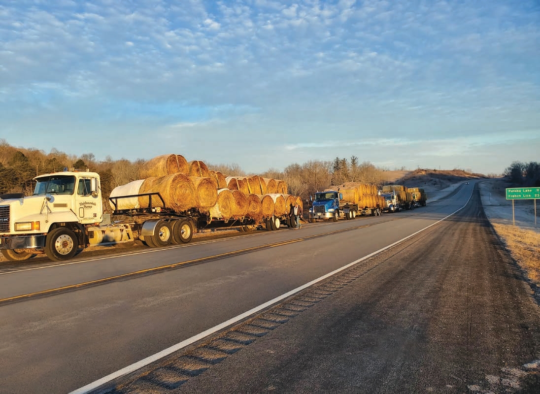 @ trucks at a pit stop to check the condition of the hay load