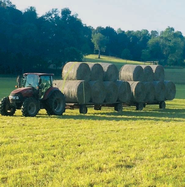 Operator has stacked hay bales centered on top between two bales on the bottom.