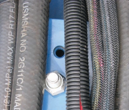 The hose on the left is not protected and rubbing against a metal bolt, which and can cause it to break down prematurely.