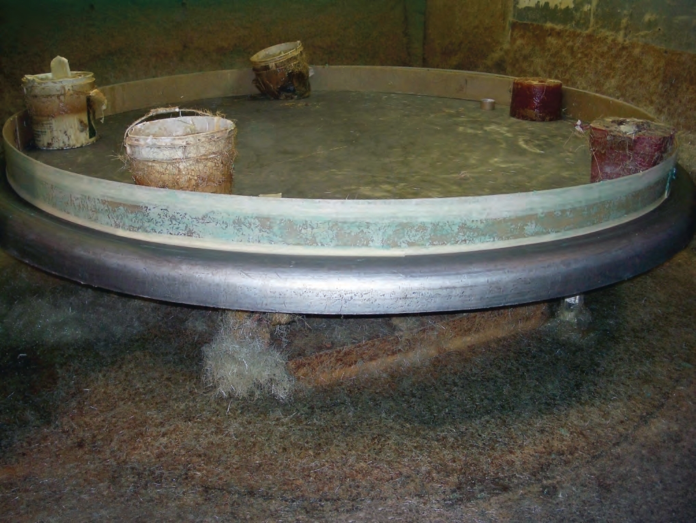 A manufacturer prepares the mold for the top of a fiberglass tank.