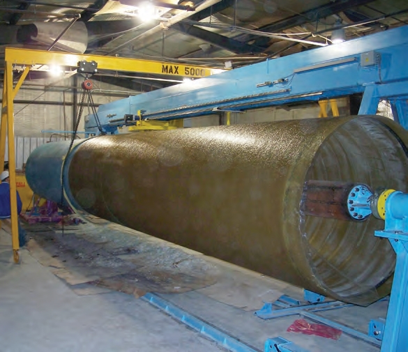 brown fiberglass tank is newly formed and is being pulled off its blue mold.