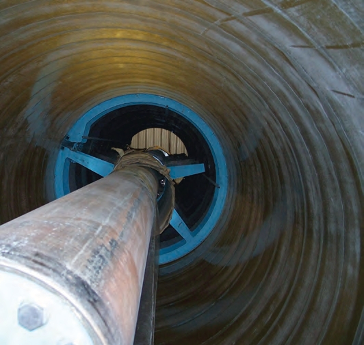 brown fiberglass tank is newly formed and is being pulled off its blue mold.