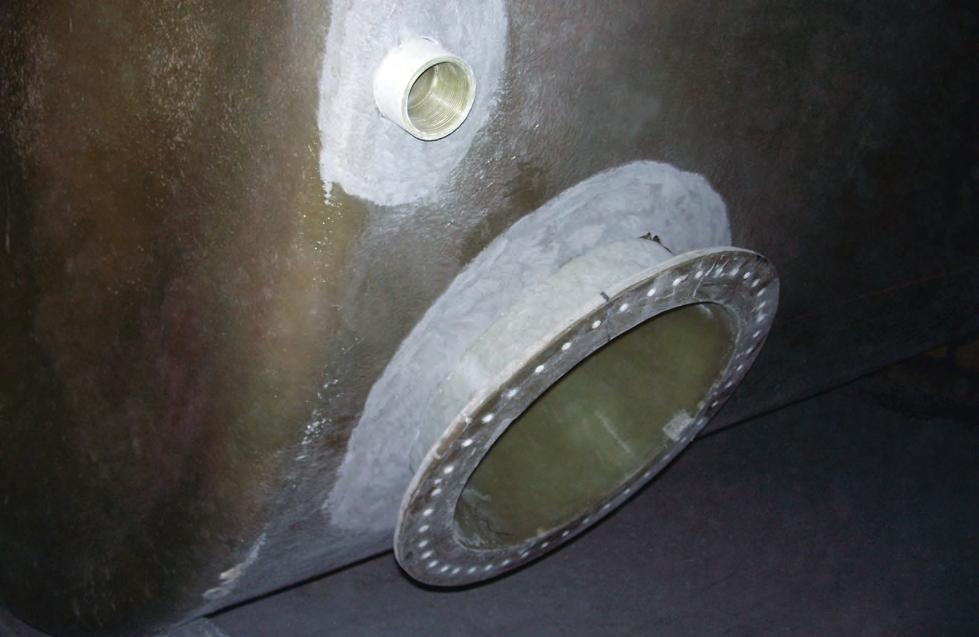 The fitting and manway are in place and ready to be glassed in on this tank. The white areas around each opening are where grinding was done to help the fiberglass and resin adhere, or bond, to the tank.